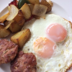 Huevos al gusto servidos con papas asadas al romero y salchicha