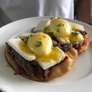 Huevos pochados sobre carne y hojaldre