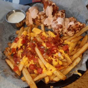 Lunch de alitas con papas y extra de queso con pico de gallo.