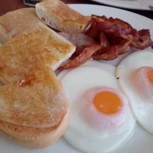 Huevos fritos, tocino y pan de la casa