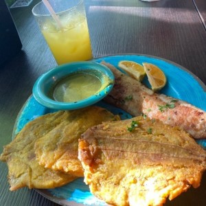 Patacones con pescado apanado y jugo de naranja