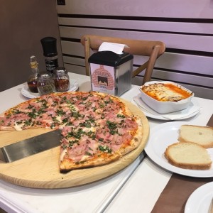 una buena pizza jamon, tocino, y albahaca super buena 