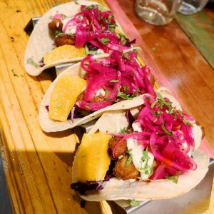 tacos de pescado frito con crema y encurtido de cebolla y rodajas de naranja