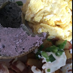 Blueberry bagel con blueberry cream cheese, huevos revuletos, papas de la casa y bacon