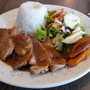 Pernil en salsa de raspadura, arroz con coco, ensalada verde y tajadas