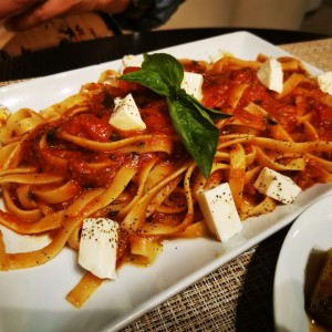 Pasta fettuccine salsa roja con queso, aceite de olvia y tomate cherry