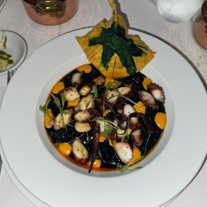 Pulpo sobre una base de arroz negro meloso.