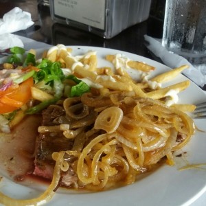 Filete de res encebollado con papas fritas y ensaladas