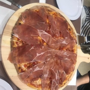 pizza de jamon serrano con trozos de tomate picados y mozzarela