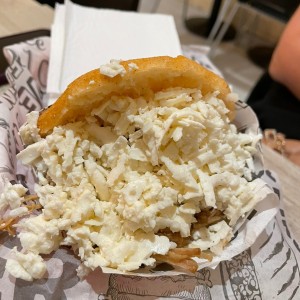 Arepa frita con pernil y queso blanco rallado.