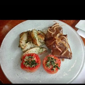 Lomo de red en cama de cebollas caramelizadas con papa y tomates al ajillo